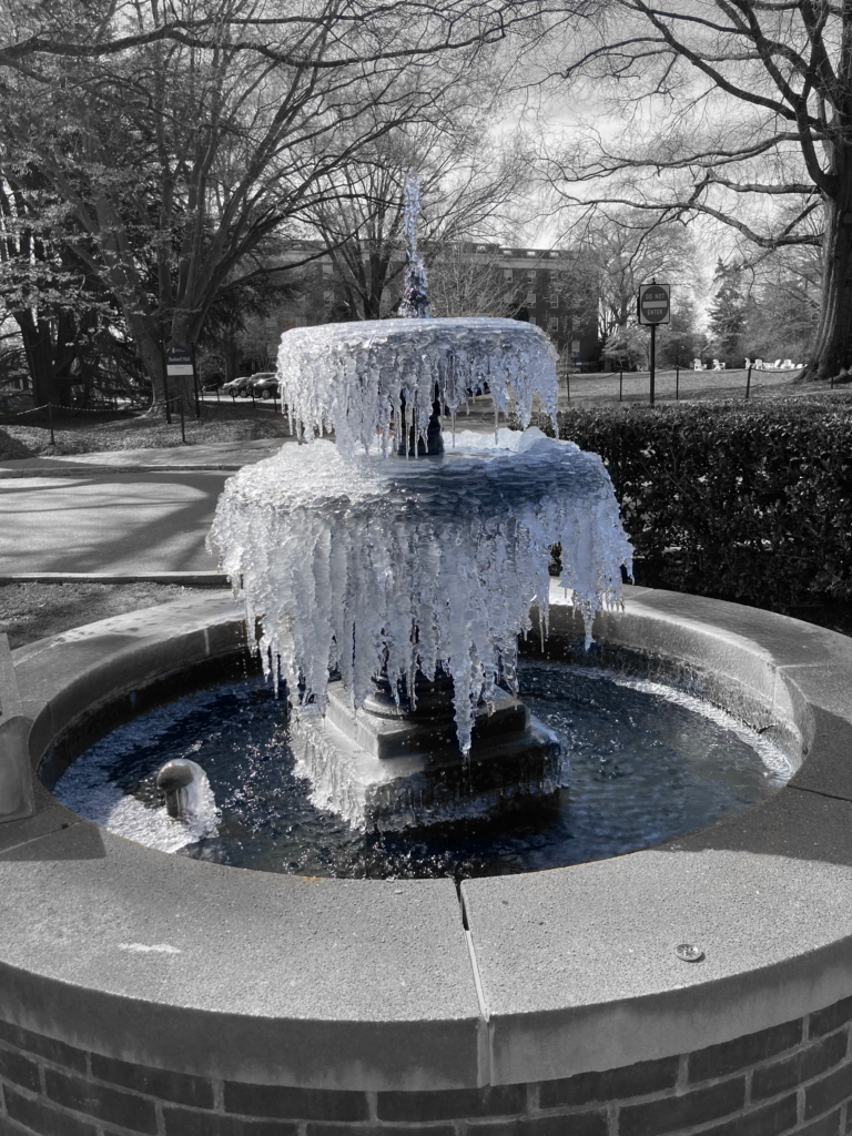 A frozen over fountain. The fountain is blueish but the background has been drained of color